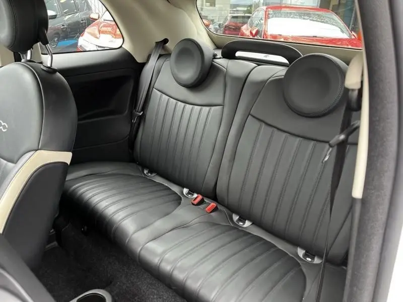 Vue intérieure arrière de la Fiat 500C blanche 2020, sièges en cuir noir avec appuie-têtes ronds distinctifs.