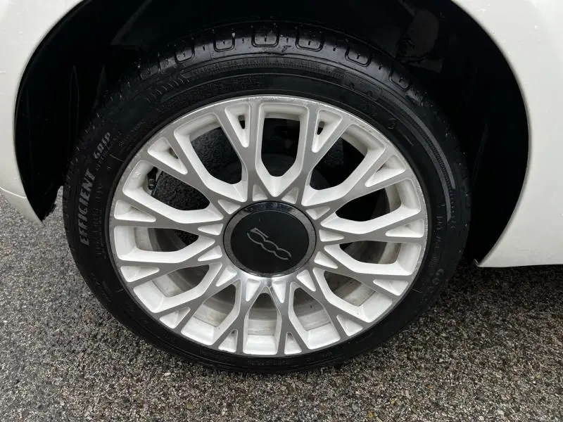 Gros plan sur la roue avant droite blanche d'une FIAT 500C 2020 avec jante en alliage au design ajouré.