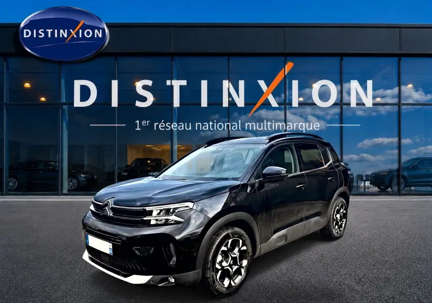 Citroën C5 Aircross noir vue 3/4 avant droit, avec jantes alu et barres de toit visibles devant showroom Distinxion.