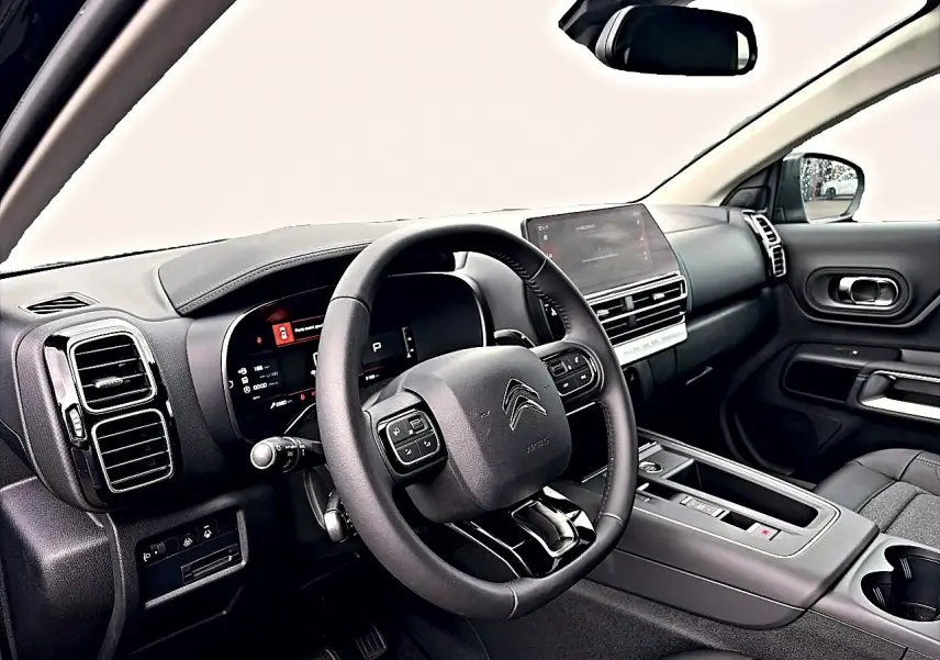 Intérieur noir du Citroën C5 Aircross 2025 vu côté conducteur, volant cuir multifonction et écran tactile central.