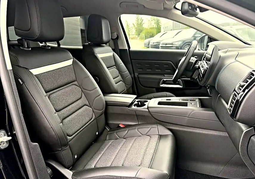Vue intérieure côté droit du Citroën C5 Aircross 2025 noir, sièges avant en cuir et tissu avec accoudoir central.