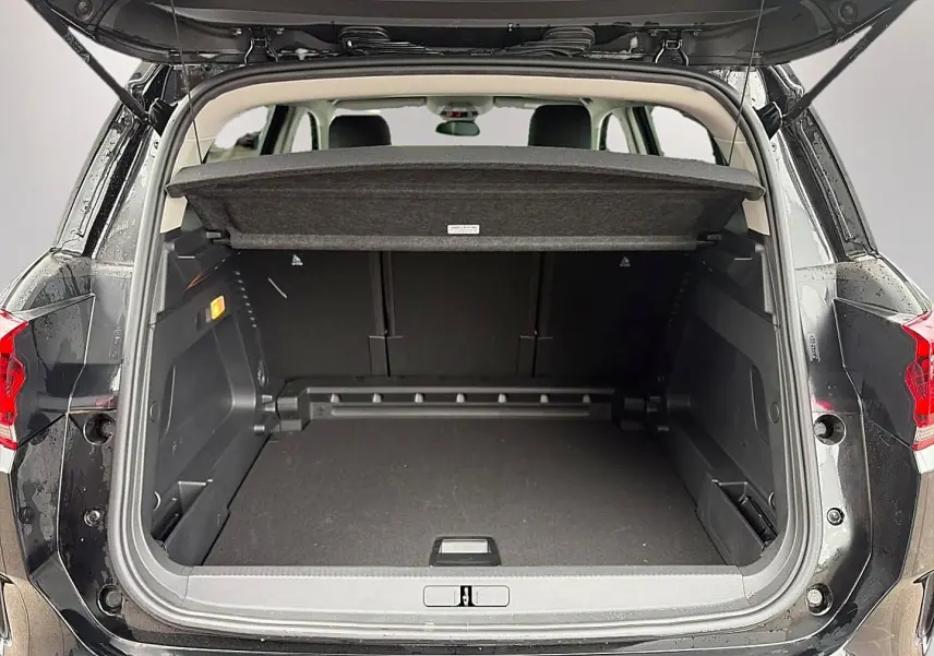Coffre ouvert vu de l'arrière d'un Citroën C5 Aircross noir 2025 avec cache-bagages et banquette arrière visible.