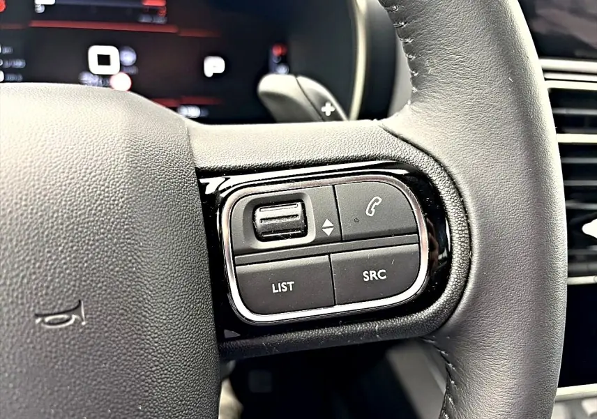 Gros plan sur les commandes multifonctions à gauche du volant cuir du Citroën C5 Aircross 2025, finition noire.