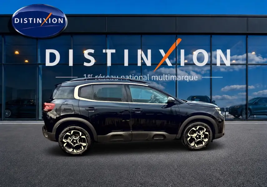 Profil droit du Citroën C5 Aircross noir 2025 avec jantes alu et barres de toit devant vitrine Distinxion.