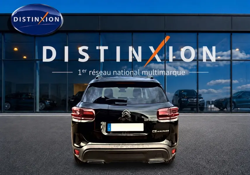 Vue arrière d'un Citroën C5 Aircross noir 2025 garé devant une vitrine avec logo Distinxion.