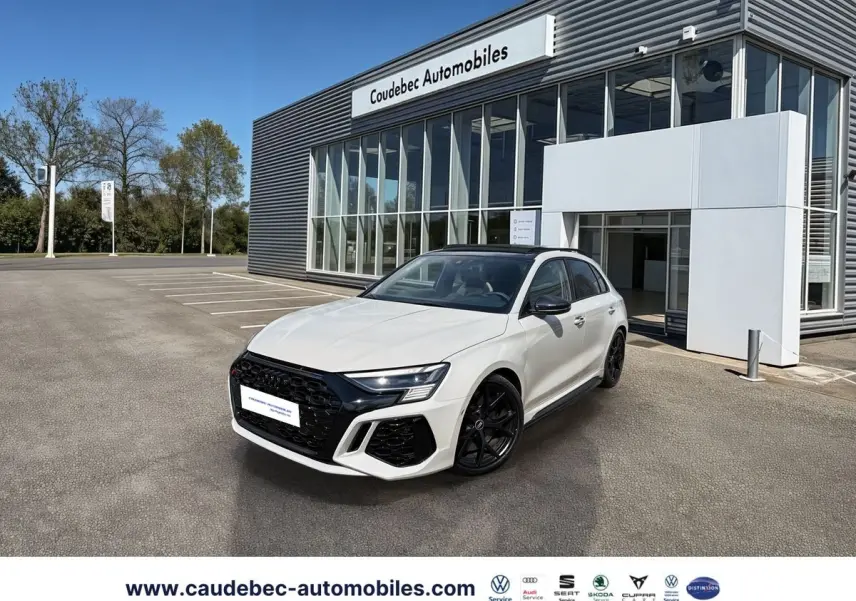 Audi RS3 Sportback gris vue 3/4 avant droit, calandre noire et jantes noires mat devant concession.