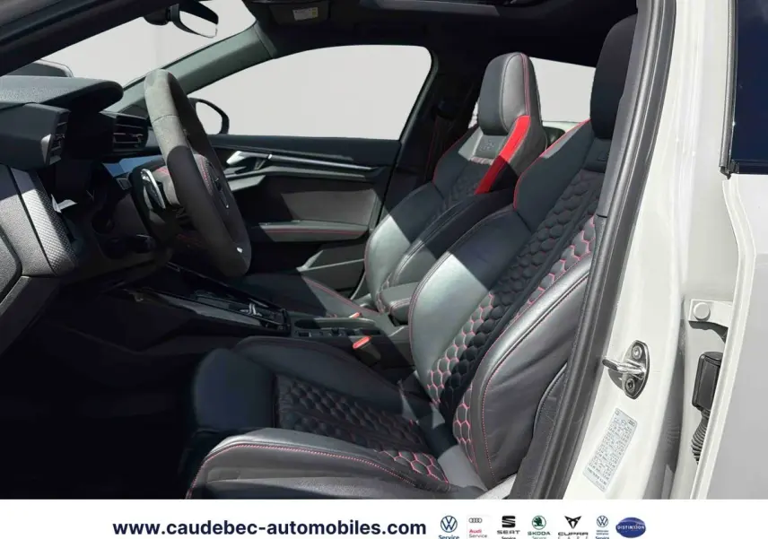 Vue intérieure côté gauche de l'Audi RS3 Sportback avec sièges sport en cuir noir à surpiqûres rouges et toit panoramique ouvert.