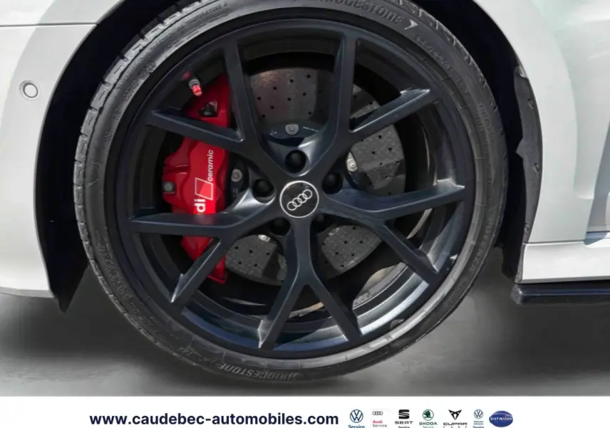 Gros plan sur la roue avant droite grise d’une Audi RS3 Sportback avec étrier de frein céramique rouge et jante noire mat à 5 branches en Y.