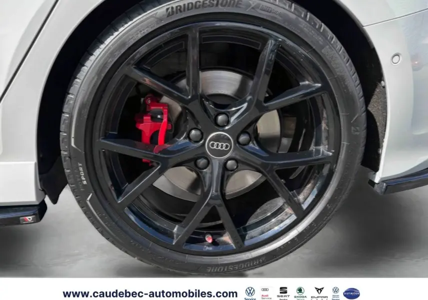 Gros plan sur la jante noire mat à 5 branches en Y avec étrier de frein rouge brillant d’une Audi RS3 Sportback grise.