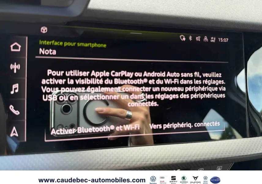 Écran tactile intérieur affichant l'interface smartphone d'une Audi RS3 Sportback grise, avec reflet de main au volant.