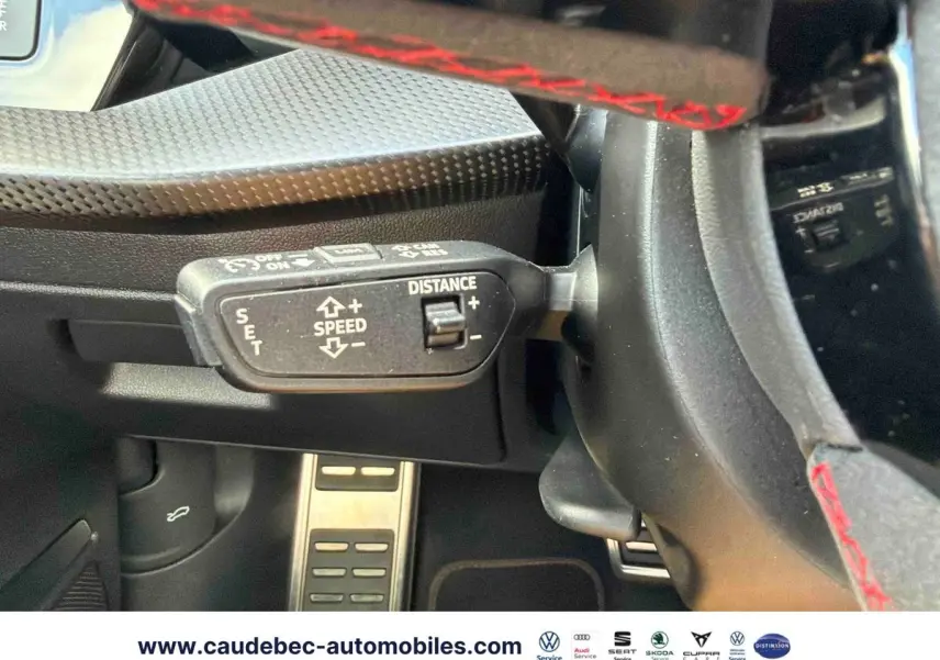 Gros plan sur la commande de régulateur de vitesse au volant d’une Audi RS3 Sportback grise avec surpiqûres rouges.