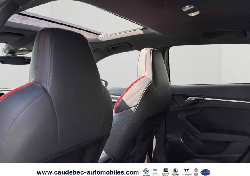 Vue intérieure arrière de l’Audi RS3 Sportback 2022, sièges cuir noir avec surpiqûres rouges et toit panoramique ouvrant.