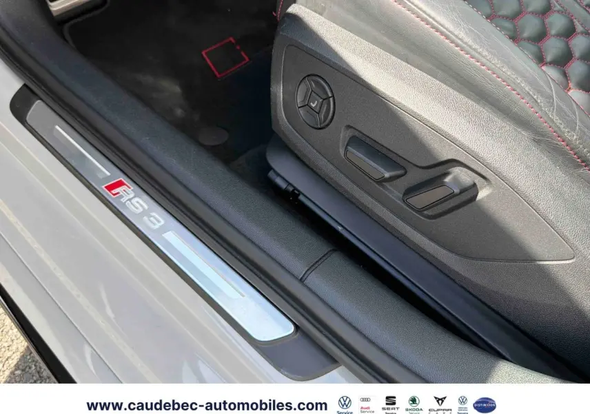 Gros plan sur la plaque de seuil RS3 et le siège en cuir noir avec surpiqûres rouges d'une Audi RS3 Sportback grise.