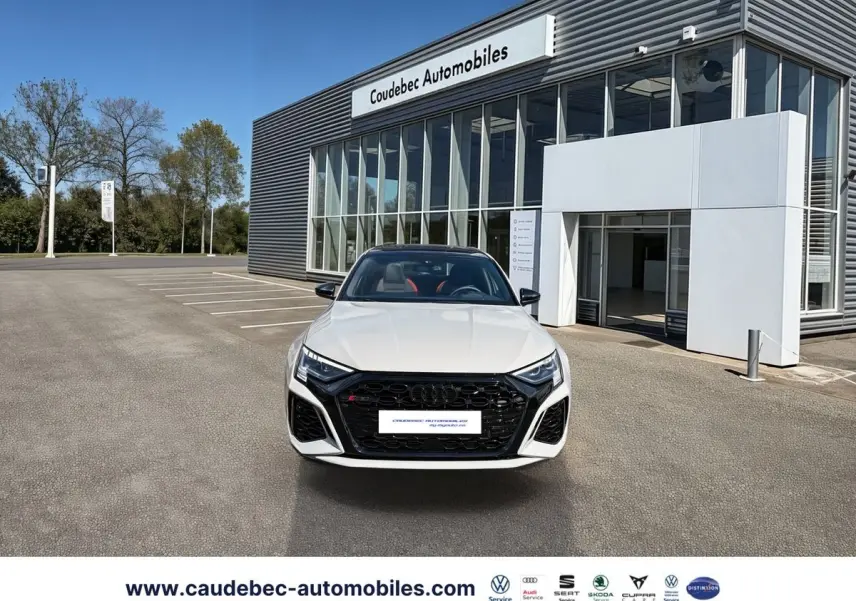 Audi RS3 Sportback vue de face en gris avec calandre noire et phares Matrix LED devant un showroom.