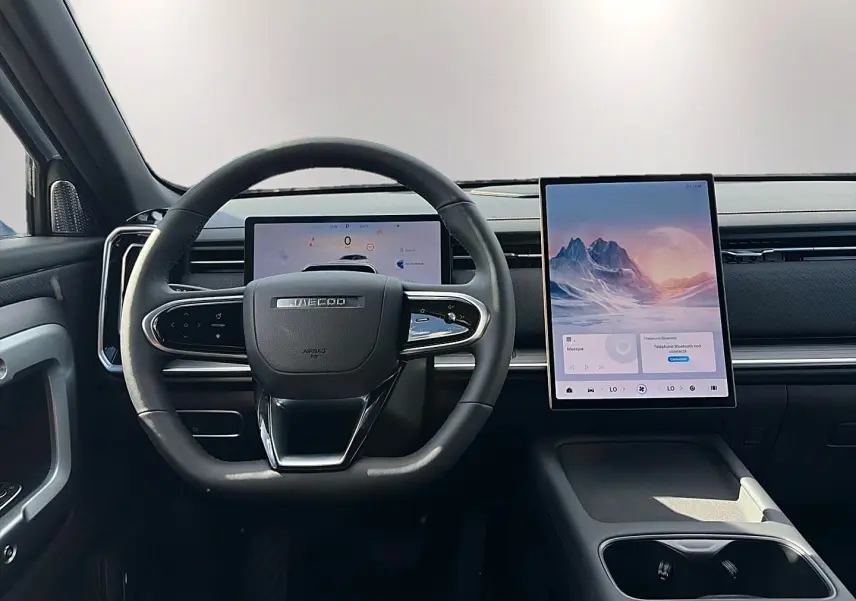 Vue intérieure centrée sur le volant JAECOO avec écran tactile vertical et tableau de bord numérique.
