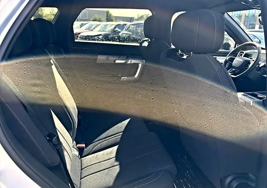 Intérieur arrière du JAECOO J7 gris moonlight, vue côté gauche montrant les sièges et partie avant avec volant.