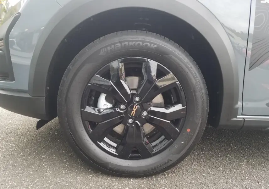 Gros plan sur la roue avant gauche du Dacia Jogger gris urbain, mettant en valeur la jante noire brillante et le pneu Hankook.