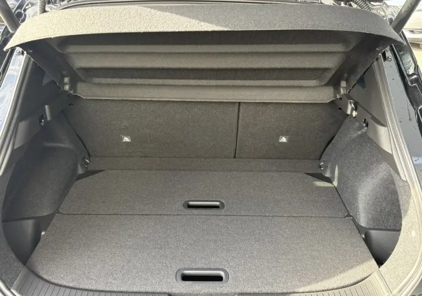 Coffre ouvert vu de l'arrière du Nissan Qashqai III noir, montrant un plancher de coffre modulable et tapis gris.