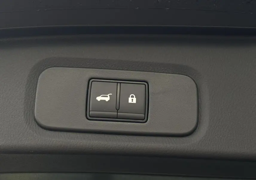 Gros plan sur les boutons d'ouverture électrique du hayon et de verrouillage dans un Nissan Qashqai noir 2025.