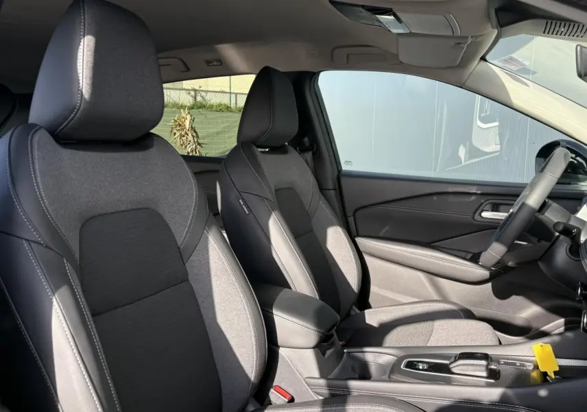 Vue intérieure côté droit du Nissan Qashqai III e-Power 2025, sièges avant gris et console centrale avec boîte auto.