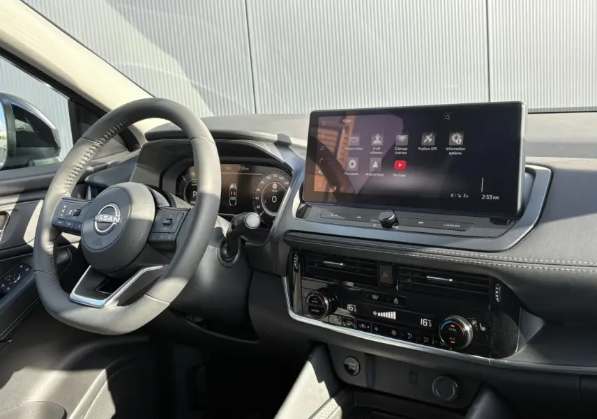 Vue intérieure côté conducteur du Nissan Qashqai 2025, tableau de bord noir avec écran tactile large et volant multifonction.