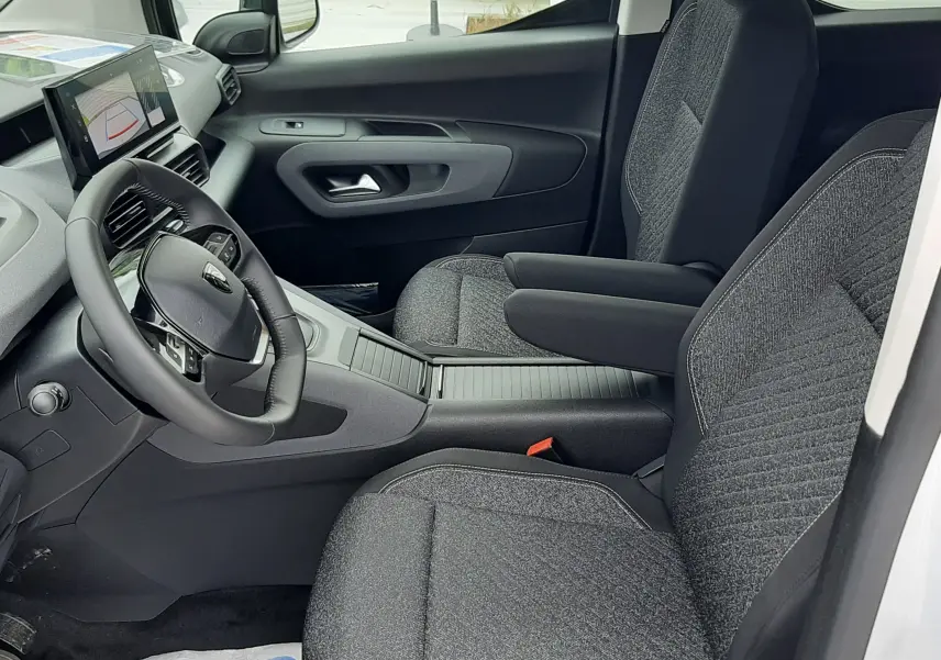 Vue intérieure côté conducteur du Peugeot Rifter 2026, sièges tissu gris et tableau de bord avec écran tactile.