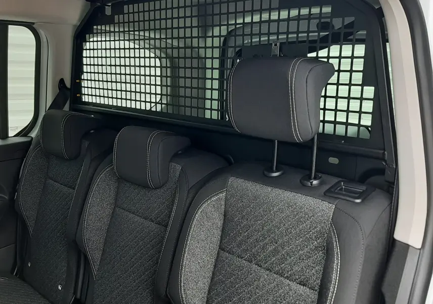 Vue intérieure arrière droite du Peugeot Rifter blanc Kaolin 2026, montrant les sièges tissu gris foncé avec grille de séparation.