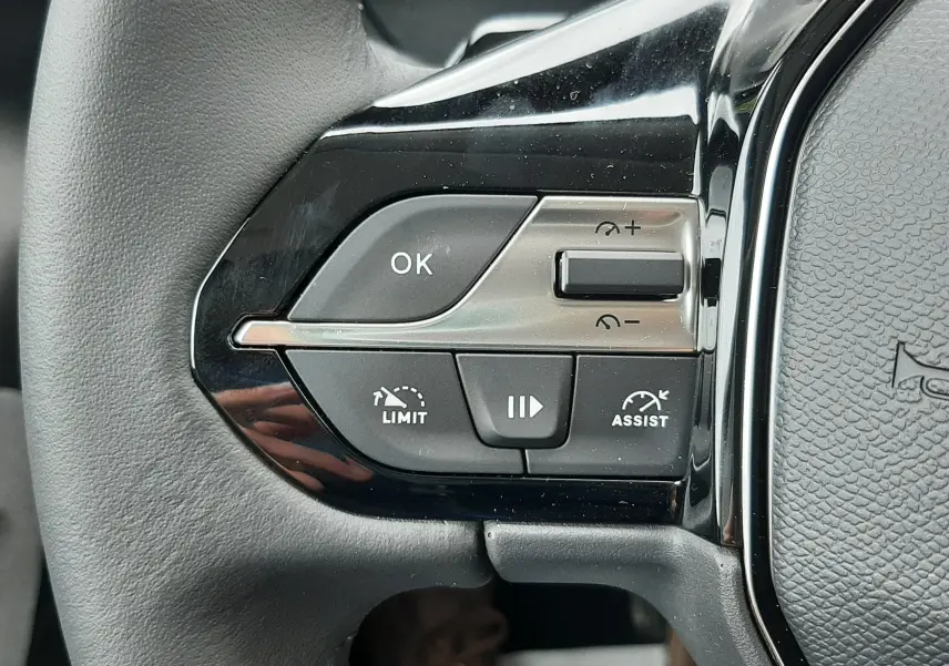 Gros plan sur les commandes gauche du volant noir du Peugeot Rifter blanc Kaolin, boutons de régulateur et assistant de conduite.