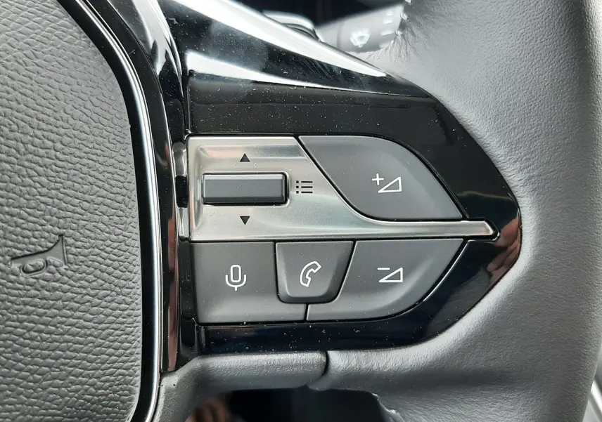 Gros plan sur les commandes multifonctions à droite du volant en cuir noir du Peugeot Rifter blanc Kaolin 2026.