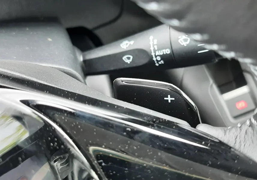 Gros plan sur la commande de palette de changement de vitesse "+" côté droit du volant d'un Peugeot Rifter blanc Kaolin.