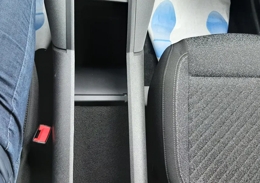 Vue plongeante sur la console centrale noire et les sièges tissu gris foncé à motifs du Peugeot Rifter blanc Kaolin.