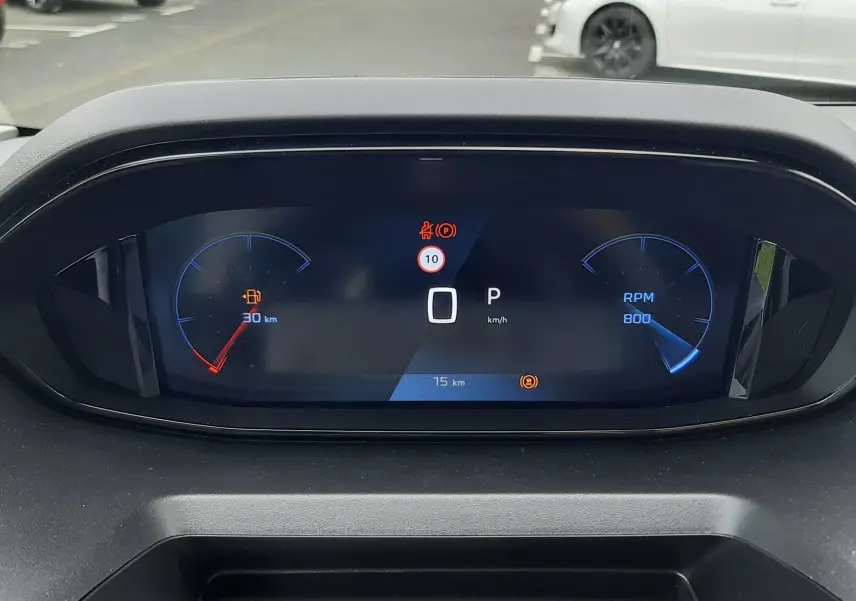 Tableau de bord numérique du Peugeot Rifter blanc, affichant vitesse à 0 km/h et jauge de carburant presque vide.