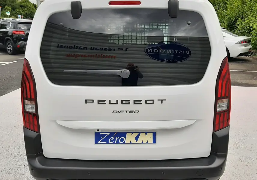 Vue arrière d'un Peugeot Rifter blanc Kaolin avec hayon noir et feux arrière verticaux rouges.