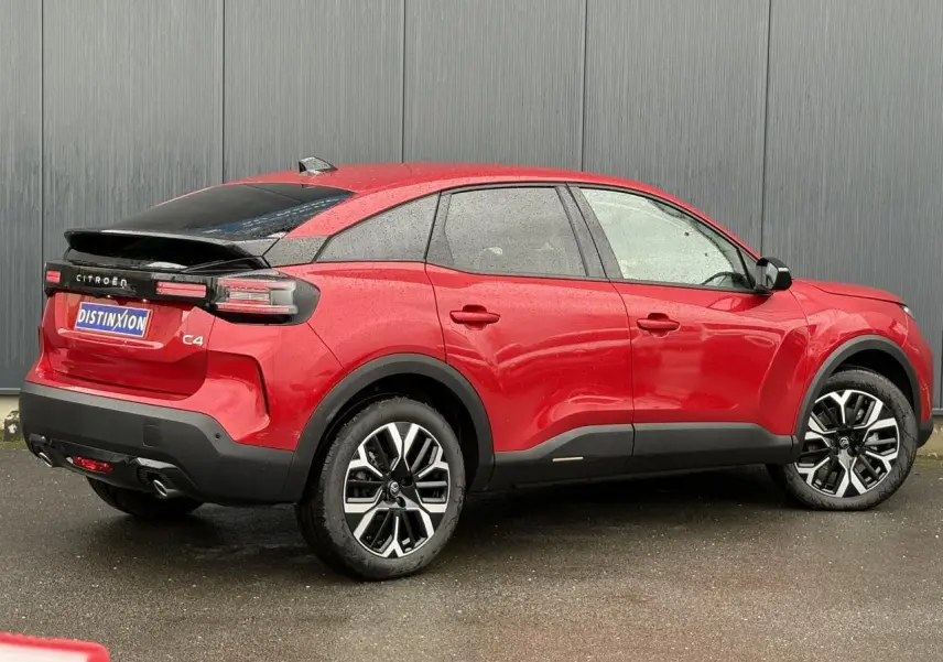 Vue 3/4 arrière droite d'une Citroën C4 rouge Elixir avec jantes alliage et toit noir contrasté.