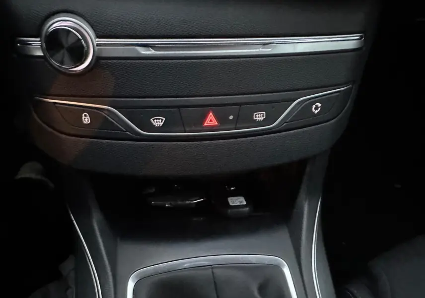 Détail de la console centrale noire de la Peugeot 308 avec les boutons de verrouillage, dégivrage et alerte au centre.