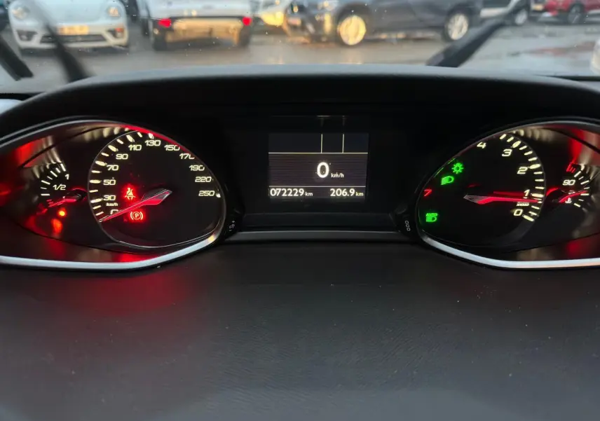 Vue rapprochée du tableau de bord numérique de la Peugeot 308 gris Artense, affichant 72 229 km et témoins allumés.