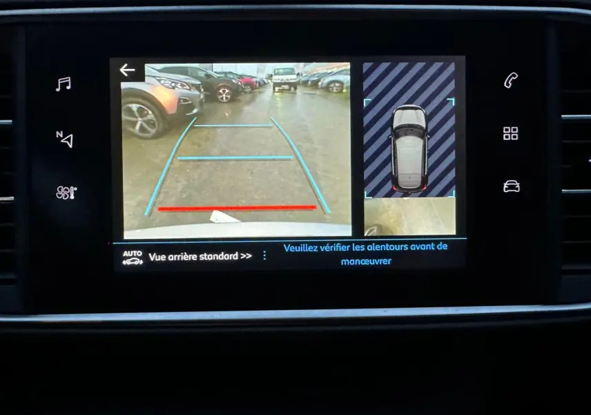 Écran tactile de la Peugeot 308 gris Artense montrant la caméra de recul avec aides visuelles au stationnement.