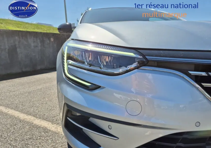 Gros plan sur le phare avant gauche d’une Renault Mégane Break gris Titanium avec détails LED et calandre chromée.