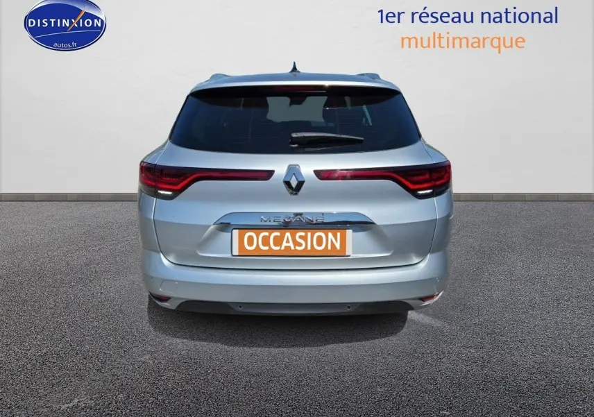 Vue arrière d'une Renault Mégane Break gris titanium 2024 avec feux LED et barres de toit visibles.