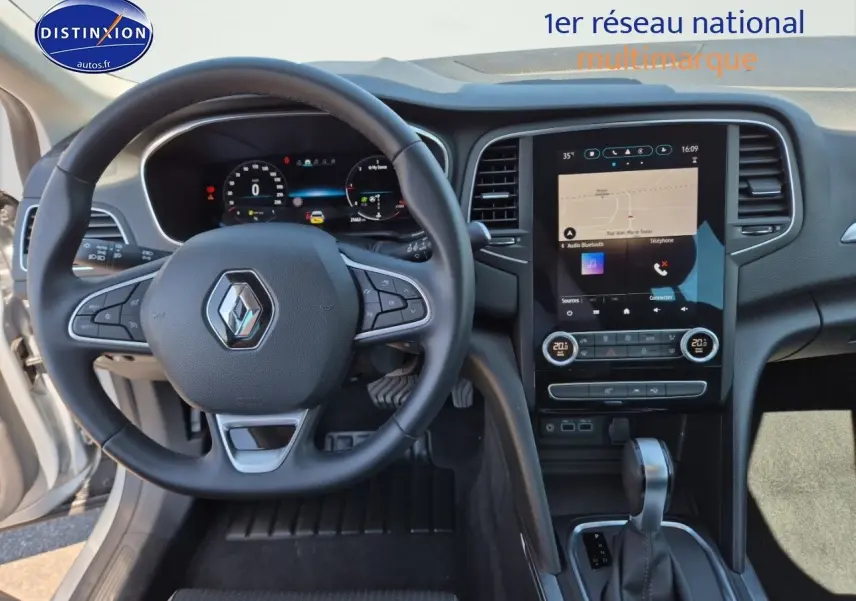 Vue intérieure centrée sur le volant multifonction et l’écran tactile du tableau de bord de la Renault Mégane Break gris Titanium.