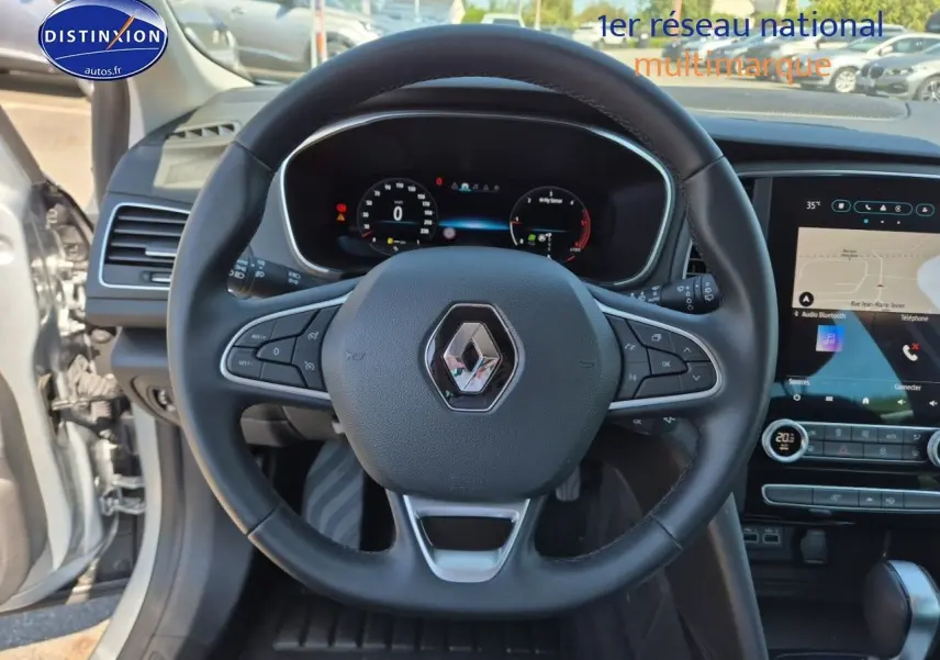 Vue centrée sur le volant multifonction noir du Renault Mégane Break 2024 avec tableau de bord digital et écran tactile.