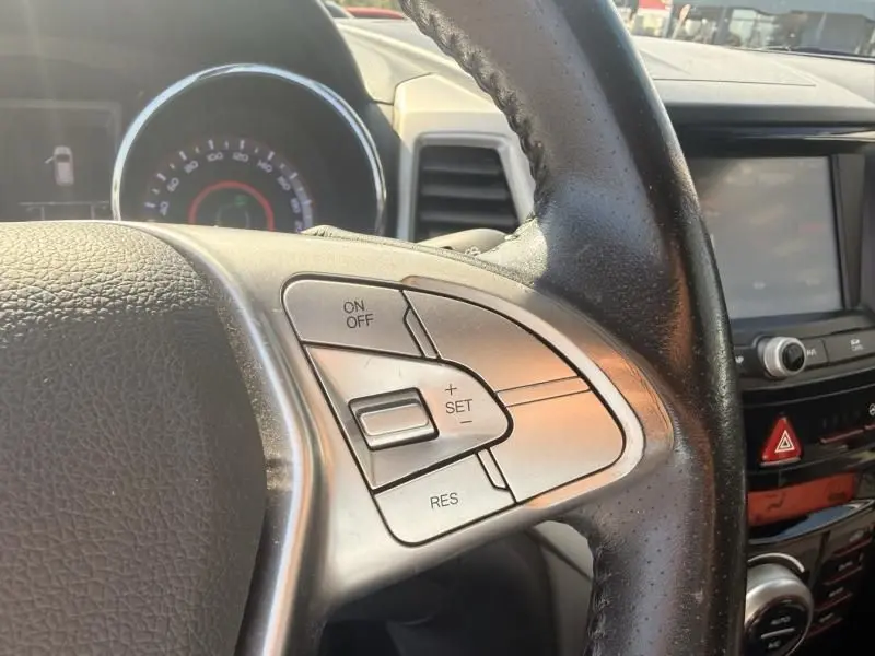 Gros plan sur les commandes de régulateur de vitesse au volant noir du SsangYong Tivoli blanc, intérieur 2017.