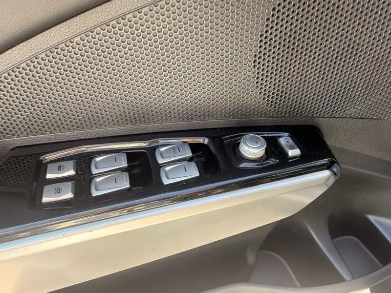 Gros plan sur les commandes des vitres et rétroviseurs côté conducteur du SSANGYONG TIVOLI blanc de 2017.