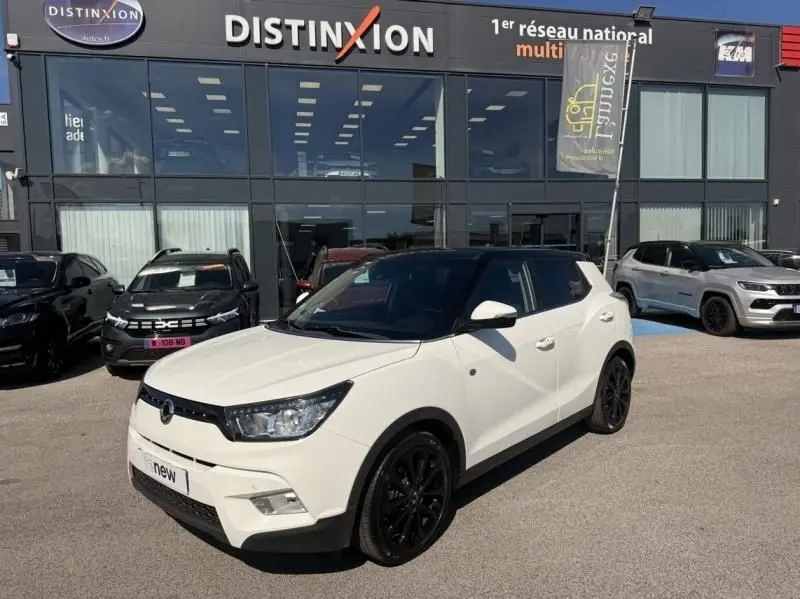 Vue 3/4 avant droite d'un SsangYong Tivoli blanc 2017 avec toit noir et jantes noires, devant un concessionnaire Distinxion.