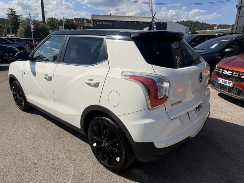 Vue 3/4 arrière droite d'un SsangYong Tivoli blanc avec toit noir et jantes noires, stationné en extérieur.