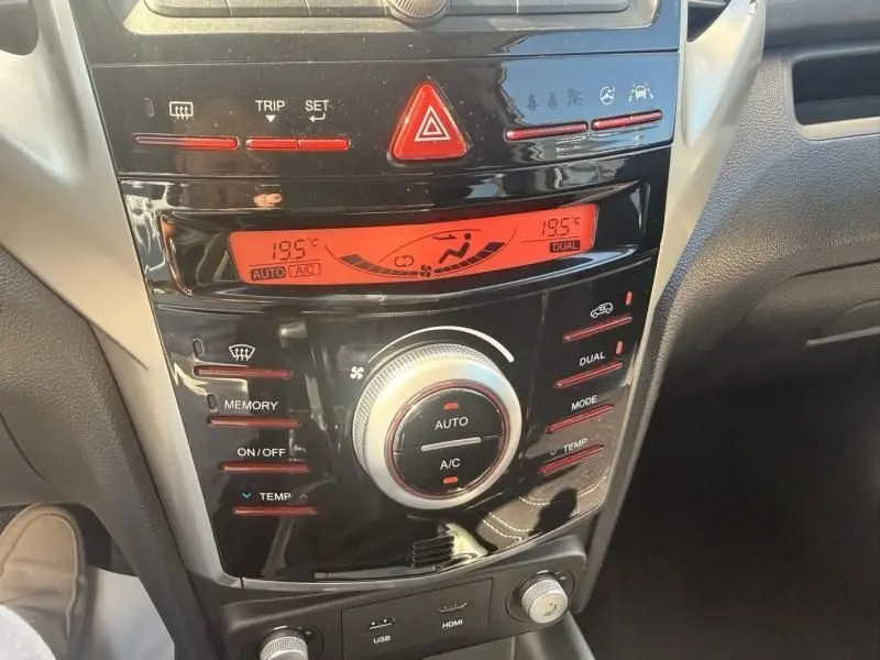 Gros plan sur la console centrale noire du SsangYong Tivoli blanc, montrant les commandes de climatisation et l'écran digital rouge.