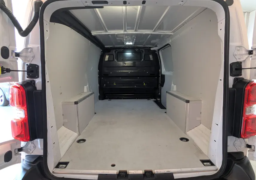 Vue intérieure arrière du fourgon blanc FIAT Scudo XL 145 EAT8 2024, montrant l’espace de chargement vide et les parois latérales.