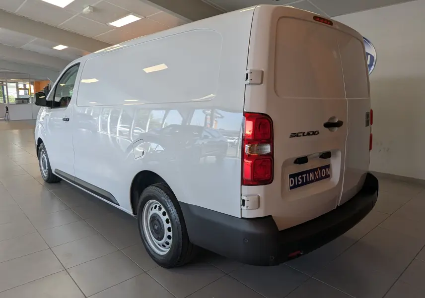 Fiat Scudo Fourgon XL blanc vu en 3/4 arrière droit dans un showroom, avec jantes tôles 16 pouces et pare-chocs noirs.
