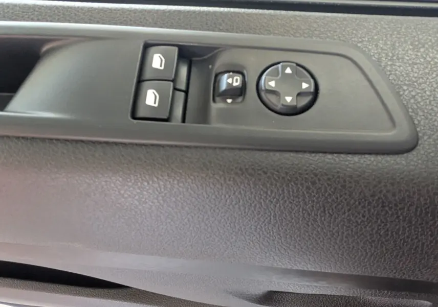 Gros plan sur les commandes de réglage des rétroviseurs et des vitres électriques sur la porte intérieure noire du Fiat Scudo Fourgon XL 2024.