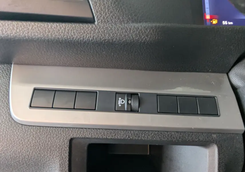 Gros plan sur le tableau de bord gris du Fiat Scudo Fourgon XL 145 EAT8 2024, avec commande de réglage des phares.